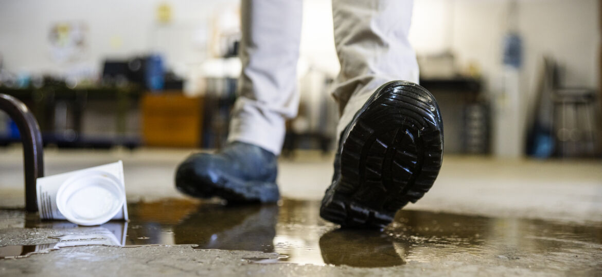 A worker in a warehouse walking in spilled liquid.