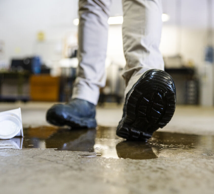 A worker in a warehouse walking in spilled liquid.