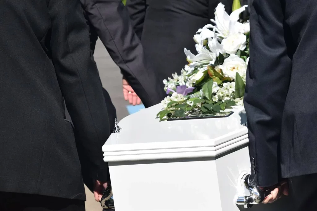 white coffin being carried at funeral