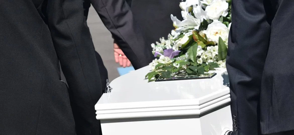 white coffin being carried at funeral